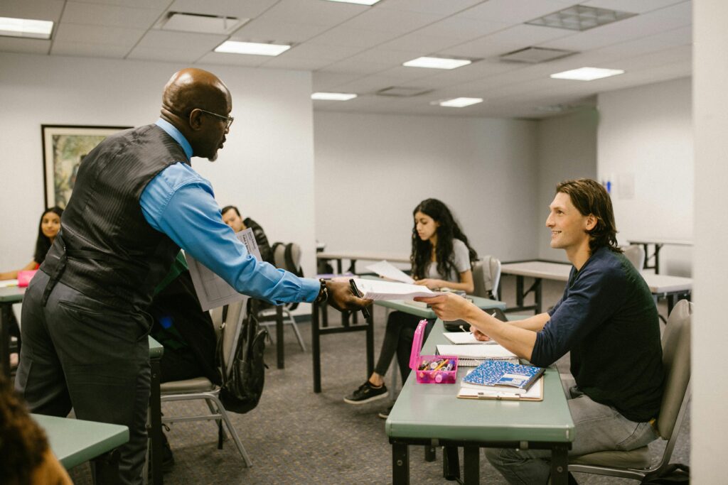A teacher engaging with students in a university classroom, promoting active learning.