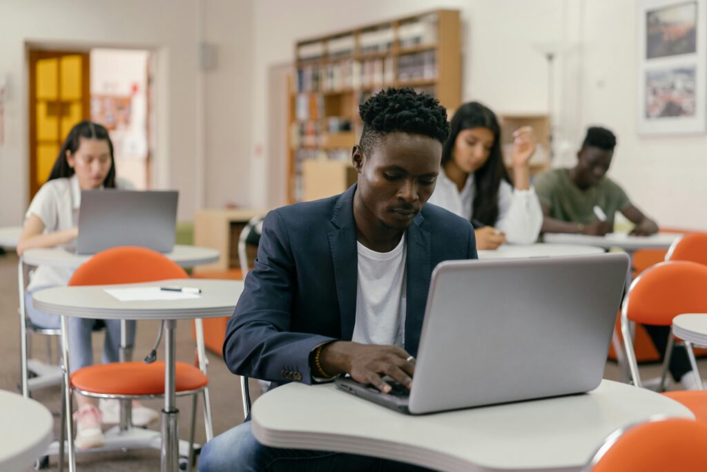 Diverse group of students studying with laptops in a modern classroom environment.